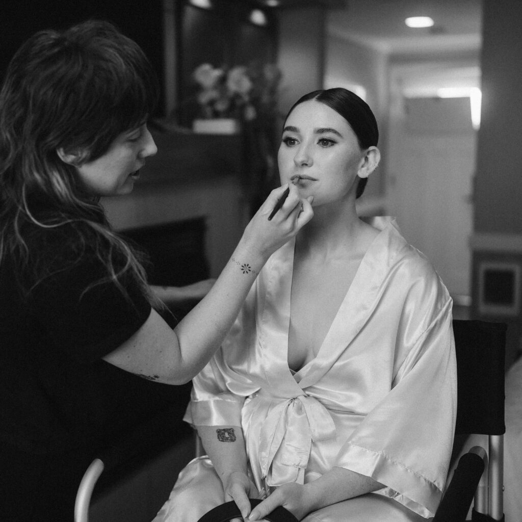 Wedding hair and makeup artist, Alyssa Underwood, working her magic on a bride in a silk robe on the morning of her intimate wedding day. 