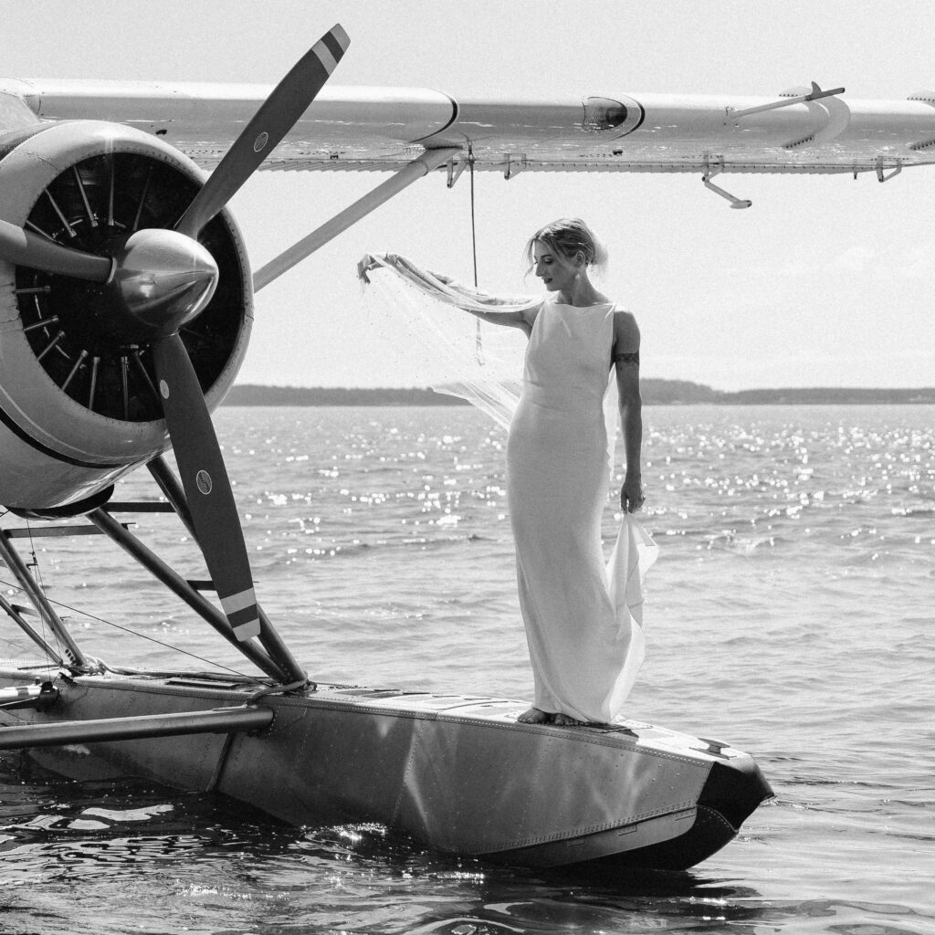 A bride dressed in a simple silk dress, playing with her veil on the float of a sea plane in the ocean nearby Orcas Island, Washington. 