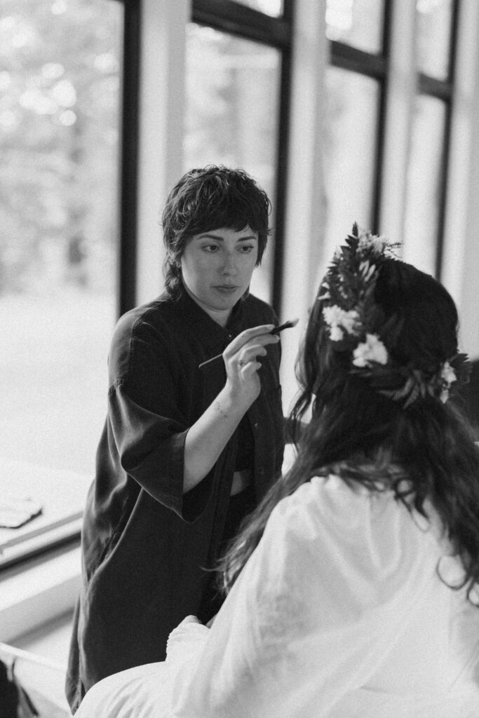 Wedding hair and makeup artist, Alyssa Underwood, putting the finishing touches on a bride on her micro wedding day. 