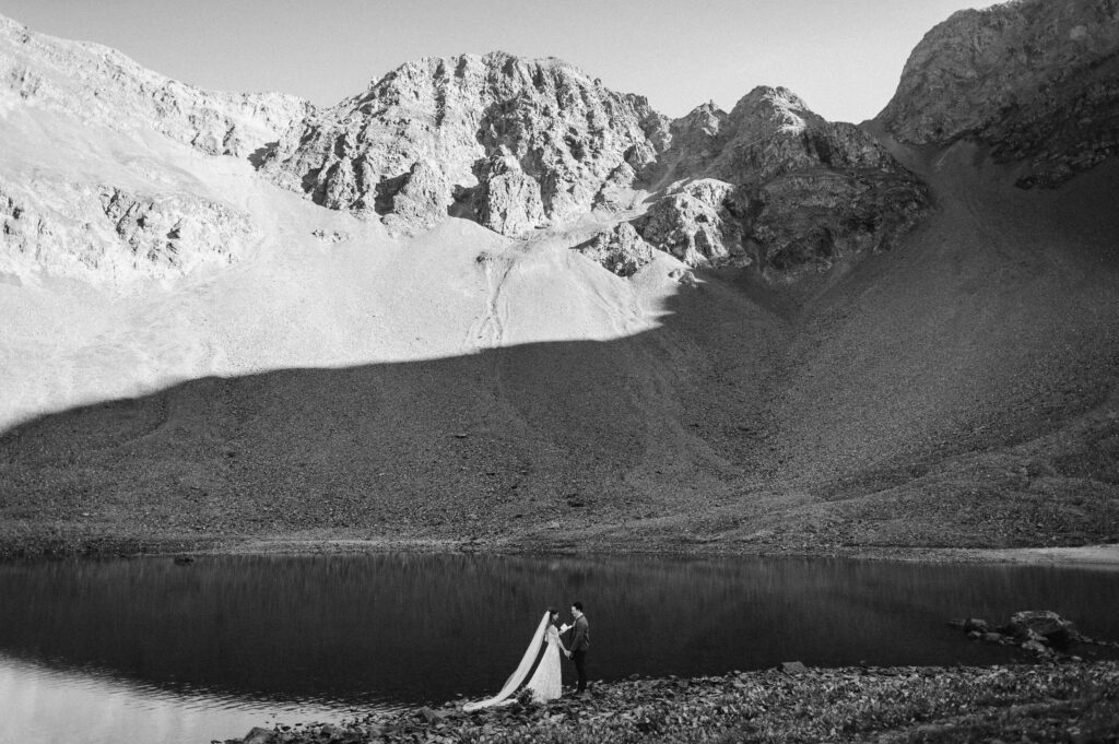 A couple experiencing the benefits of eloping, just the two of them, on the edge of an alpine lake in the Colorado San Juan mountains.