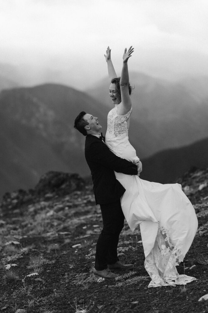 A couple celebrating with bliss after exchanging vows on top of a mountain in Olympic National Park during their blissful wedding.