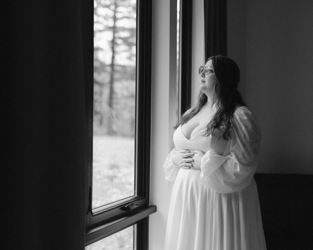 black and white photo of bride looking out window on her oregon elopement day