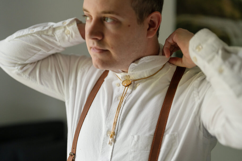 groom putting on a bolo tie